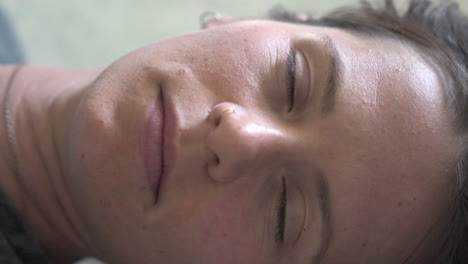 a close-up of a woman lying on the ground, looking directly into the camera. the camera slowly turns around her, creating an intimate and captivating perspective.