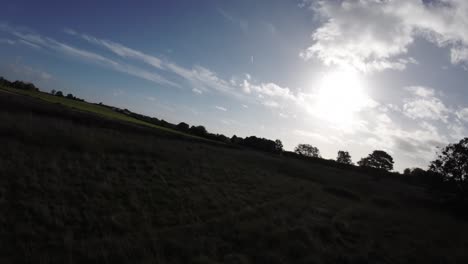 FPV-drone-flying-low-across-countryside-agricultural-farmland-grass-meadow