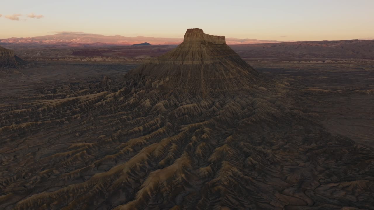 Distant Factory Butte rising above vast desert plains in Utah southwest, aerial orbit backdrop