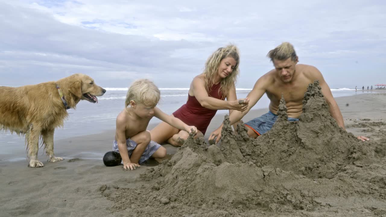 семья строит песчаные замки на океанском пляже.