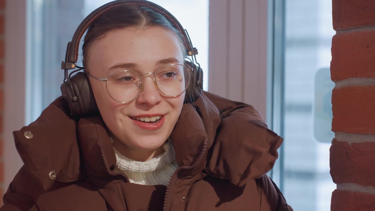 Young Woman in Headphones and Winter Jacket Warming Hands and Waving