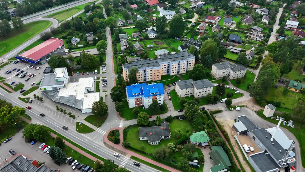 Drone orbit of Ikskile, Latvia building rooftops, parking areas, and street layouts, multi use buildings