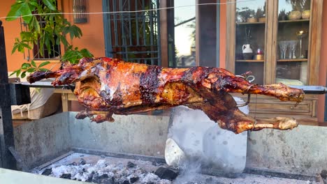 roasting whole lamb on a spit metal rotating stick over fire, golden crispy skin, lamb bbq grill, delicious meat, 4k shot