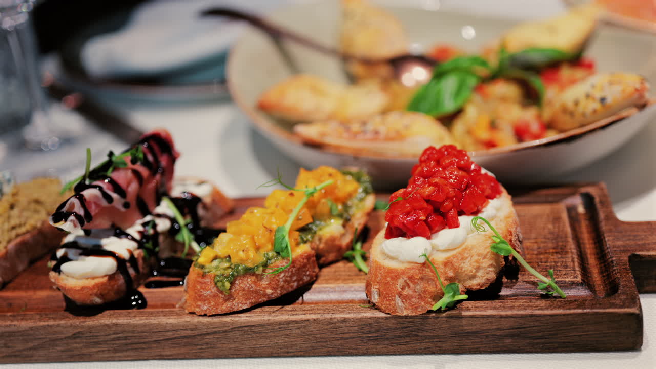 Close up of rustic bruschetta topped with cream cheese and roasted red peppers, garnished with fresh greens