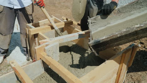 work with concrete at the construction site workers take concrete into a wooden mold heavy manual la