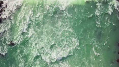 Slow-flyover-of-turbulent-turquoise-river-and-wide-waterfall-in-Iceland