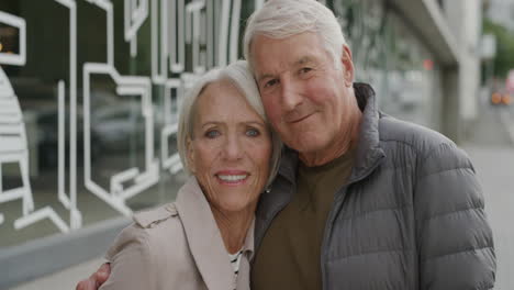 portrait of happy elderly couple hugging smiling embracing enjoying togetherness looking at camera in urban city street successful relationship