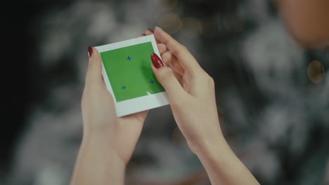 woman holding a green screen polaroid picture