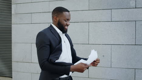 african businessman reading documents on street. employee going for job outdoors