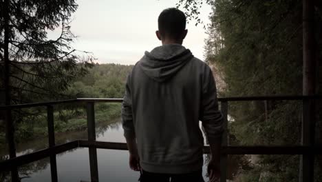 hombre contemplando una mañana brumosa junto a un río en el bosque