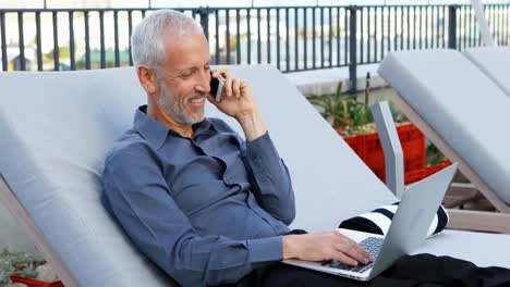 Businessman-talking-on-mobile-phone-while-using-laptop-4k