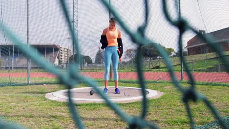 Caucasian-female-athlete-getting-ready-for-shot-put-game-at-sports-venue-4k