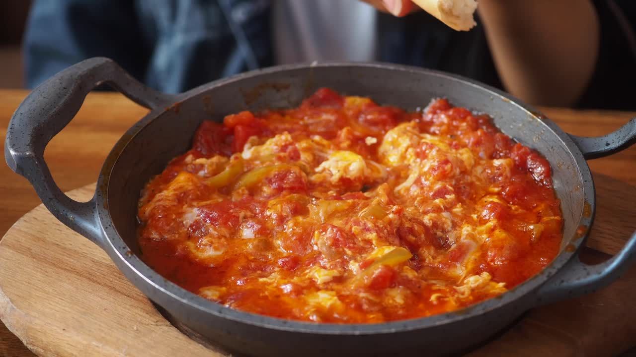 Primo piano di mano che intinge il pane nel delizioso Menemen turco