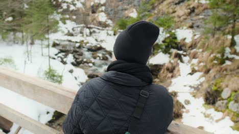 person standing on a wooden bridge in a snowy mountain landscape