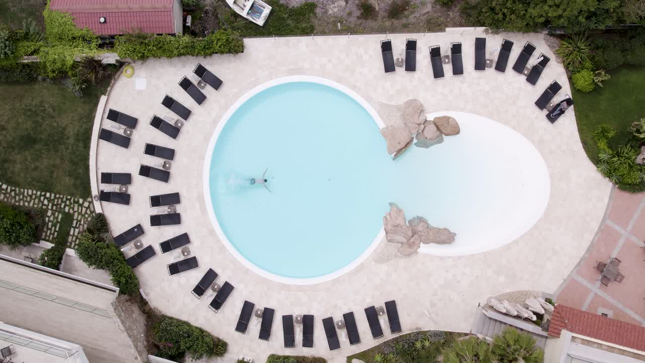 кавказский мужчина ныряет в бассейн роскошного курорта, воздушный снимок