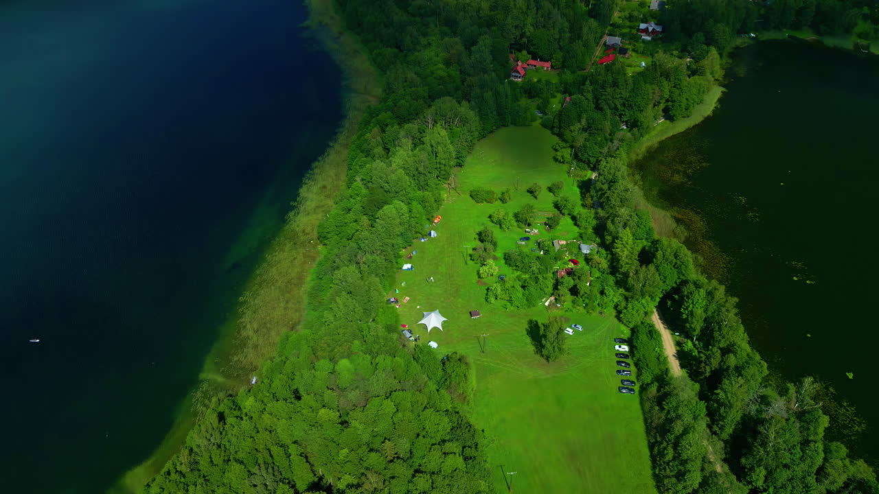 공중 드론은  ⁇ 은 날 큰 호수에 둘러싸인 울창한 초록색 식물로  ⁇ 인 아름다운 캠핑 장소를  ⁇ 습니다.