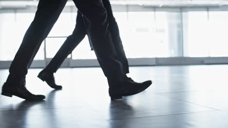 vista lateral de las piernas de hombres de negocios que caminan