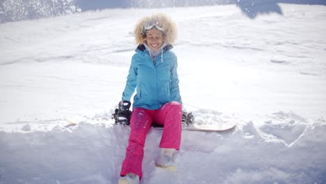 Schöne-Junge-Snowboarderin-Sitzt-Auf-Schnee