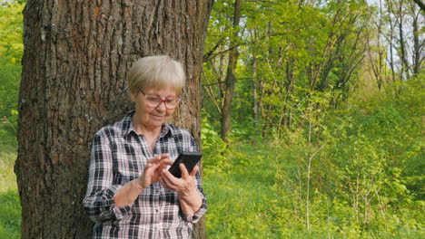 senior woman using smartphone in forest