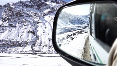 Perspectiva-Del-Espejo-Retrovisor-De-Un-Automóvil-Conducido-En-Terreno-Montañoso-Accidentado-Durante-Los-Inviernos