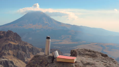 Buch-Und-Kaffee-Auf-Den-Felsen-Und-Dem-Vulkan-Popocatepetl-Im-Hintergrund