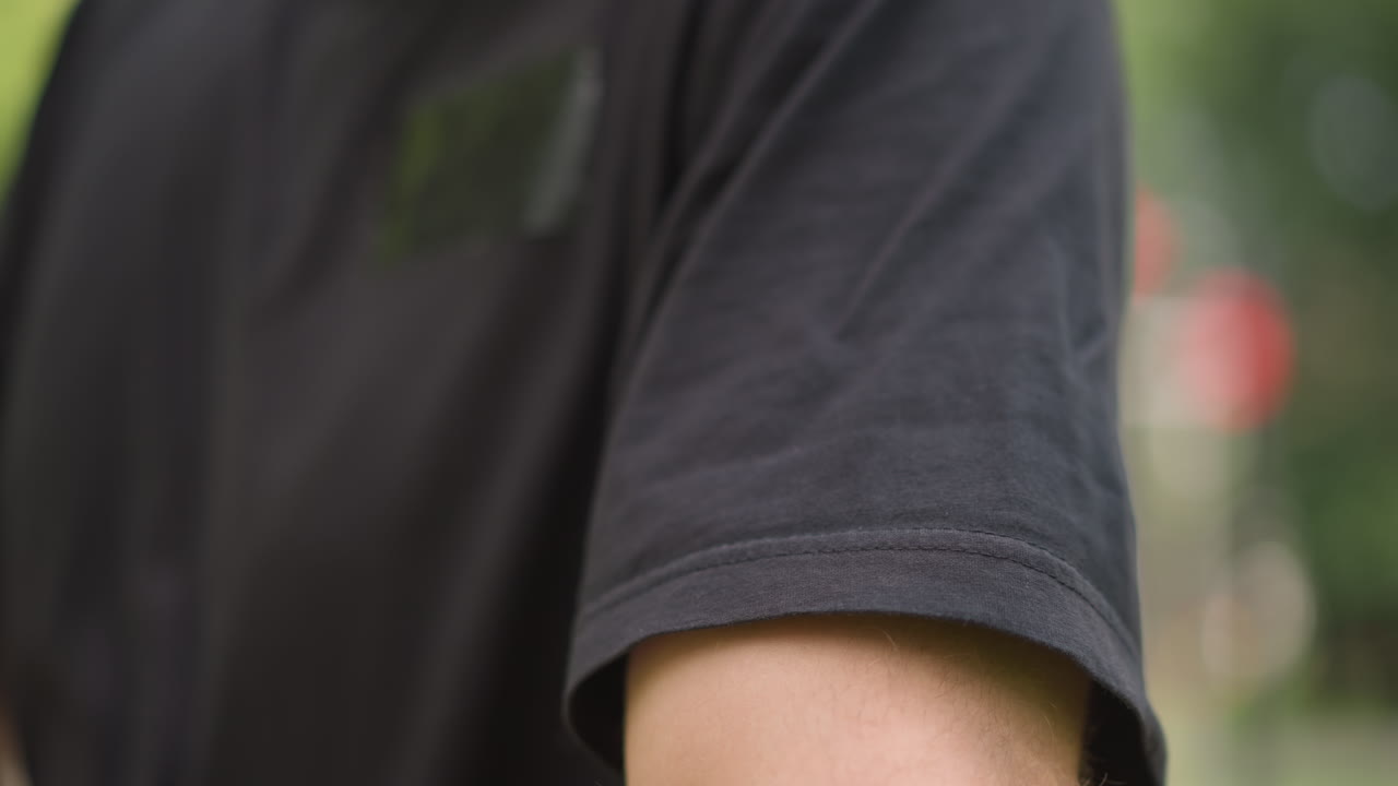 Preparing For Exercise, Closeup Of Clothing And Focused Hands, Calm Individual In Park Prepares For Physical Activity, Man Carefully Rolls His Sleeve Up In Tranquil Park Training Space
