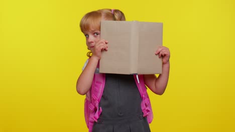 Attractive-teenage-girl-kid-in-school-uniform-wears-pink-backpack-peeping-while-hiding-behind-a-book