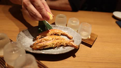 person seasoning fish with lemon at table