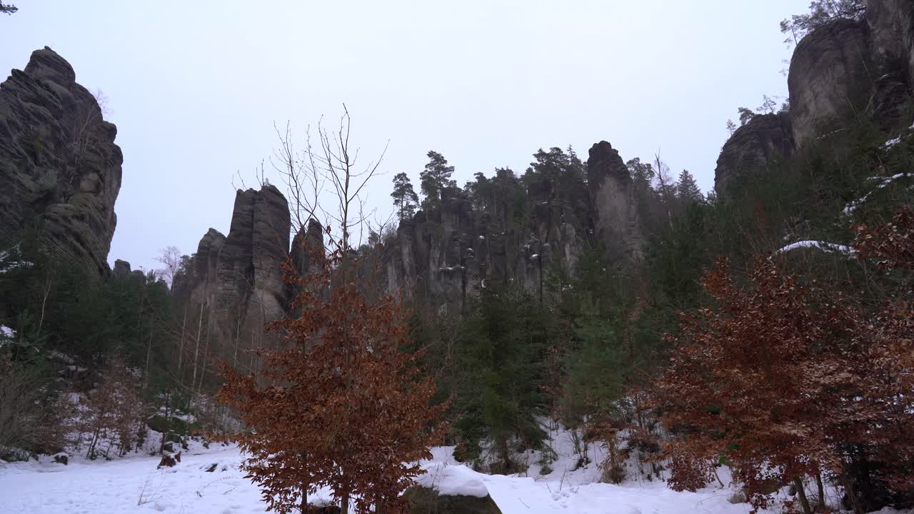 en medio de una ciudad de piedra arenisca en rocas prachov, paraíso bohemio en invierno con copos de nieve voladores, pan a la izquierda