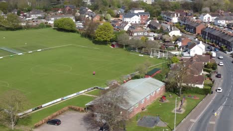 aerial drone shot panning over village football pitch and housing estate, england