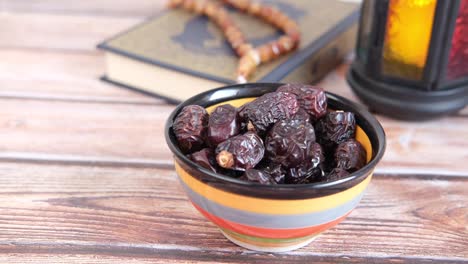 cerca de frutas de dátiles frescos en un cuenco y libro sagrado del corán en la mesa