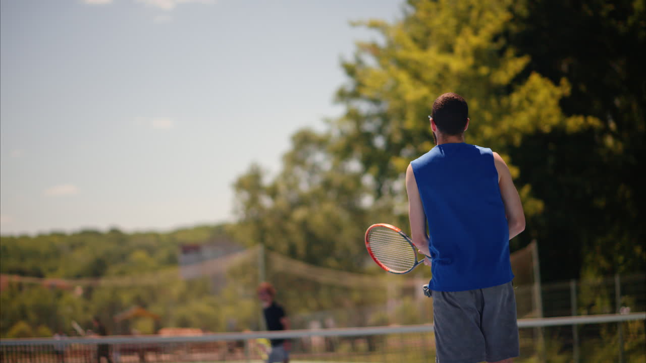 Two men playing tennis on a blue and green court on a sunny day