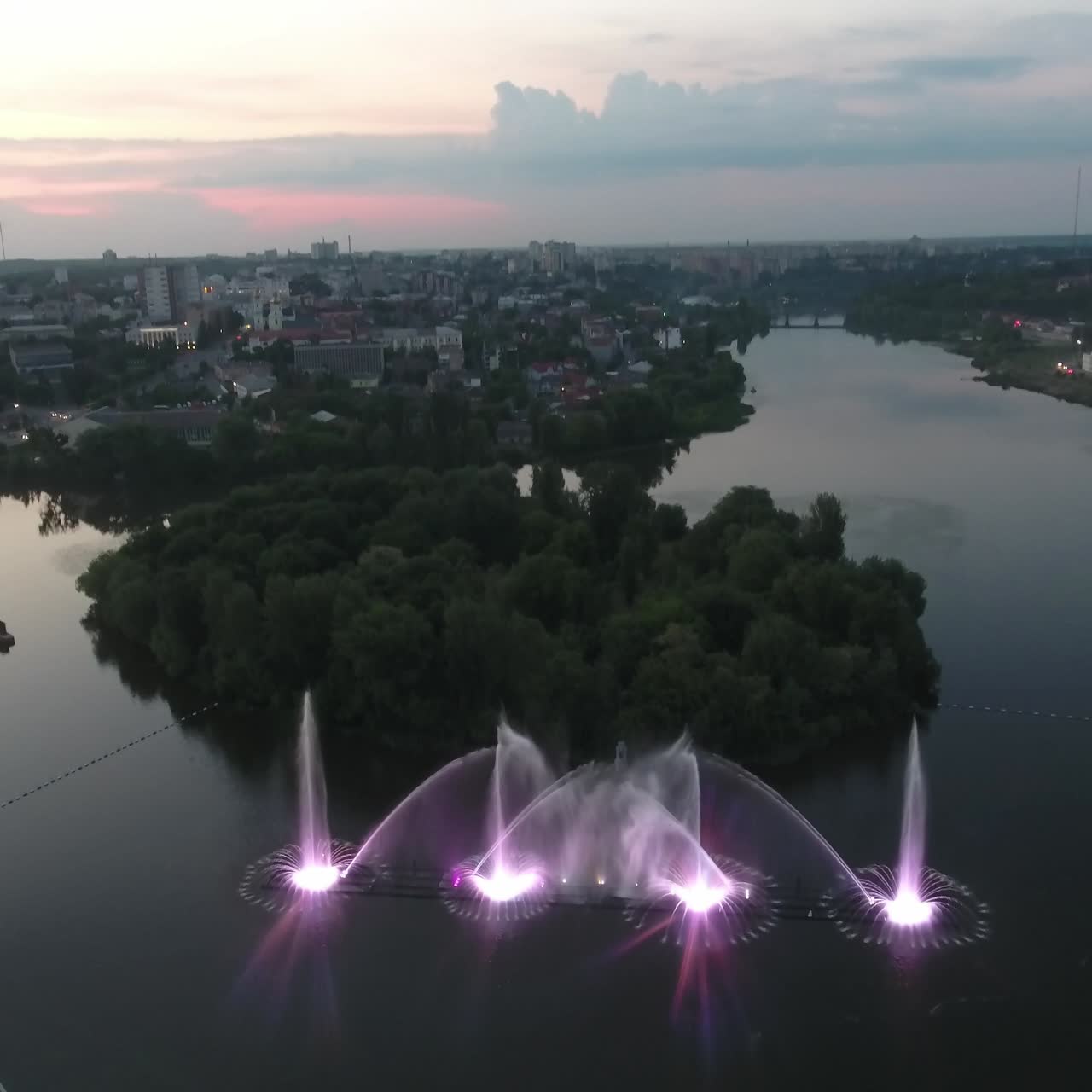 Water Music Fountain In Night. Aerial shot of the dancing colorful fountain with reflection on water at night