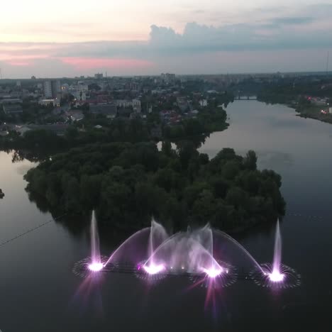 water music fountain in night. aerial shot of the dancing colorful fountain with reflection on water at night