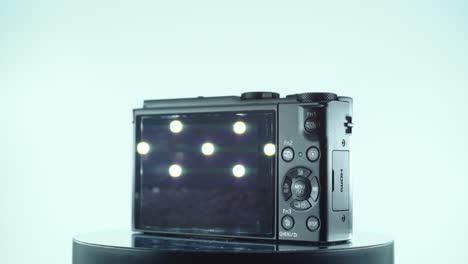 close up shot of a small black pocket camera, aluminiaum built, function buttons, lights reflecting on the screen, shiny lens, on a 360 rotating stand, slow motion, 4k video