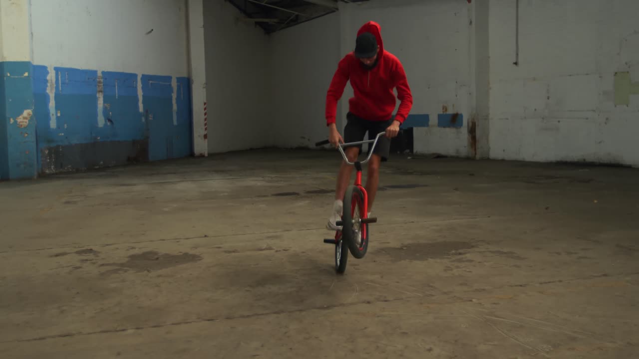 Ciclista BMX in un magazzino vuoto.