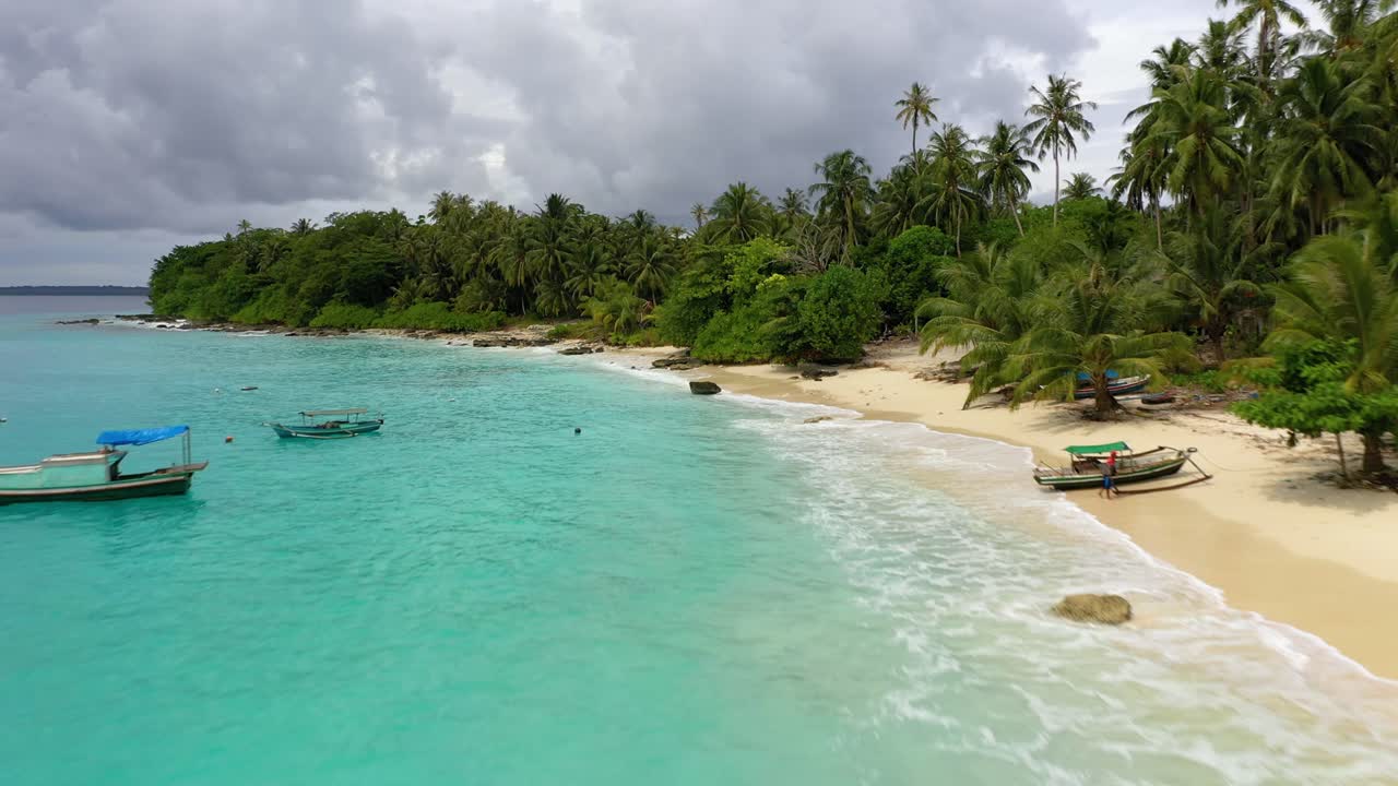 Drone che vola lungo la spiaggia con acqua incredibilmente blu e palme all'isola di Asu, Sumatra Settentrionale, Indonesia.