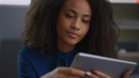 african american woman using tablet computer researching data in business work.