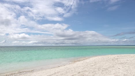 Hermosa-Agua-Azul-Del-Océano-Con-Olas-Lavando-Suavemente-En-Tierra-En-Una-Playa-Tropical-De-Arena-Blanca-Bajo-Un-Cielo-Azul-Con-Nubes-Esponjosas-En-Las-Filipinas