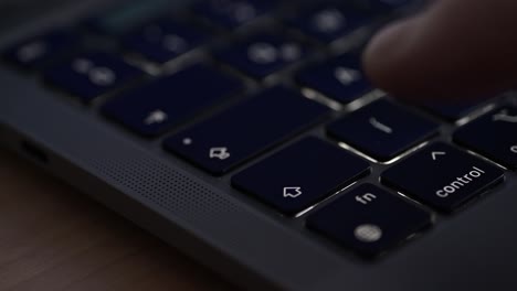 a close-up video of a person's finger pressing the right arrow key on a sleek laptop keyboard. the video highlights the dark keycaps, modern design, and the perforated speaker grille on the device
