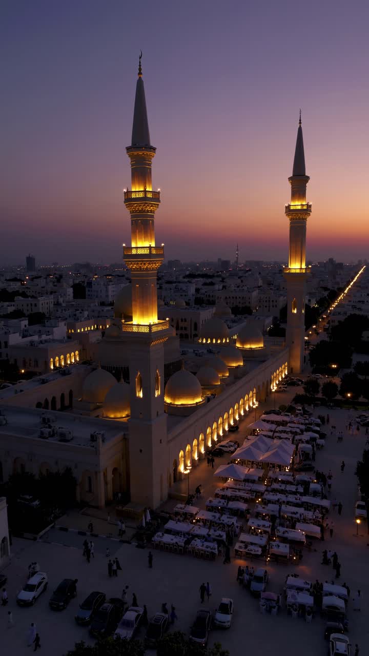 Aerial perspective revealing illuminated mosque during sunset, displaying architectural grandeur and communal gathering within Kuwait City's traditional courtyard landscape