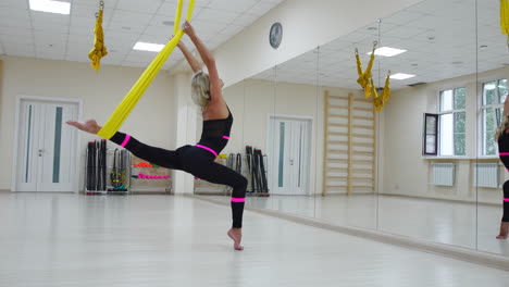 deporte concepto de estilo de vida saludable. espacio de copia. ajuste mujer joven bonita usando ropa deportiva haciendo yoga volar ejercicios de estiramiento en entrenamiento de fitness sala de clase de gimnasio blanco loft.
