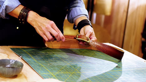 mid section of craftswoman making leather belt