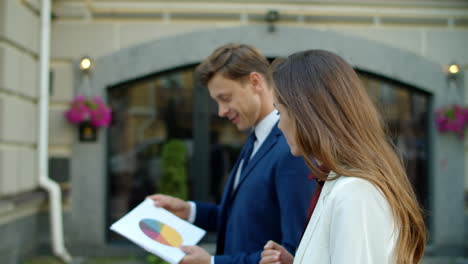 successful business couple analyzing data in papers together outdoors