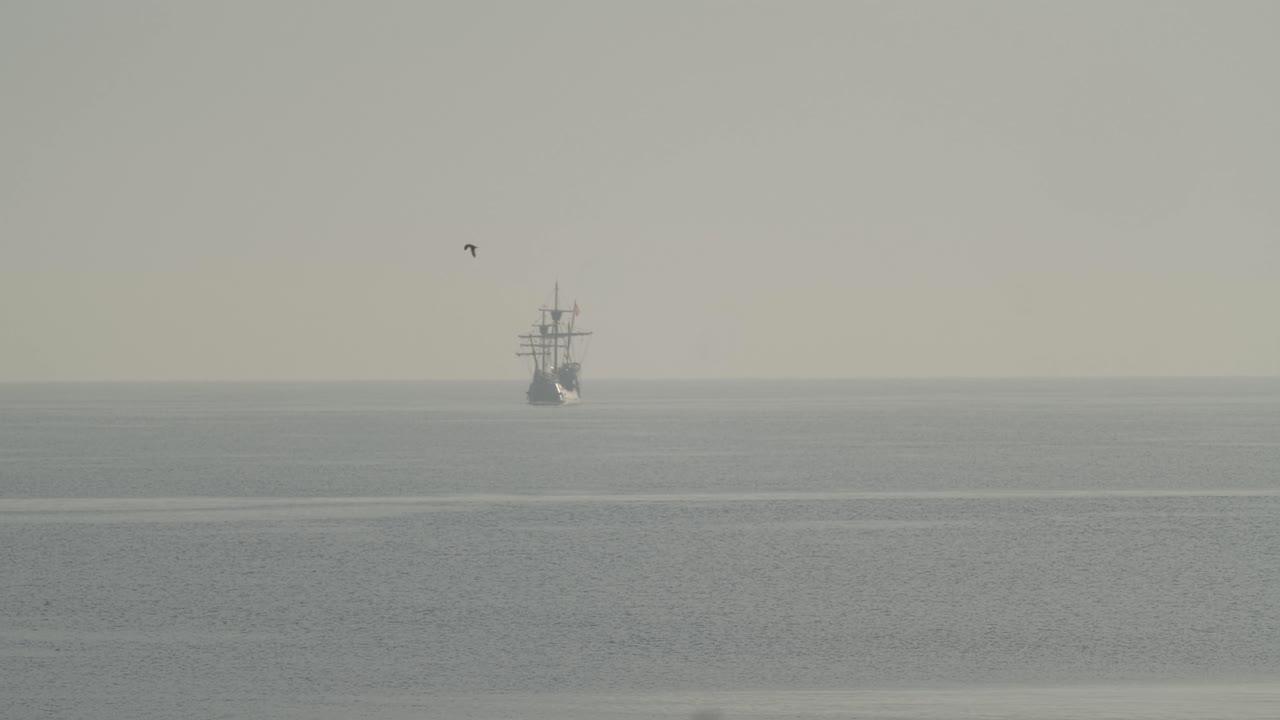 페르디난드 마젤란 나오 빅토리아 카락 보트 복제품은 일출 시 지중해에서 멀리 항해하며 새는 60fps의 느린 동작으로 잔잔한 바다에서 날아갑니다.