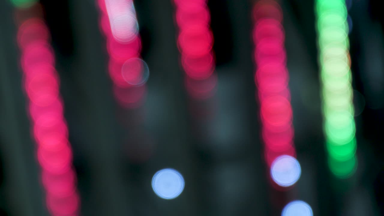 Strisce colorate rosso vivo e verdi. Linee neon sfocate con effetto bokeh. Sfondo astratto festivo. Raggi pulsanti e sfocati di luci sceniche in un locale notturno o sala da concerto. Industria dell'intrattenimento