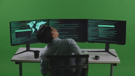 back view of asian man developer having backache while write code with multiple computer screens in green screen studio
