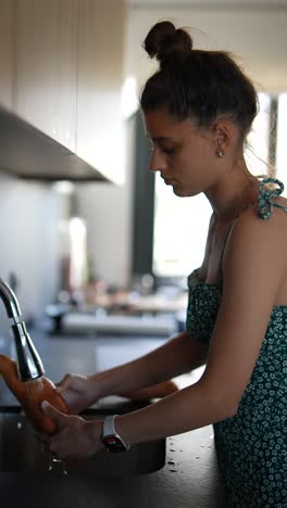 una mujer joven lavando una patata dulce en la cocina