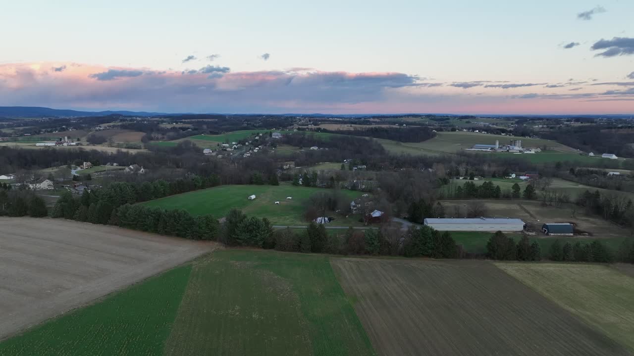 Ampia ripresa aerea con drone del paesaggio autunnale dell'America rurale, con campi ondulati, aziende agricole sparse e un tenue orizzonte color pastello. Tranquilla campagna aperta e pacifici piccoli centri degli Stati Uniti in autunno.