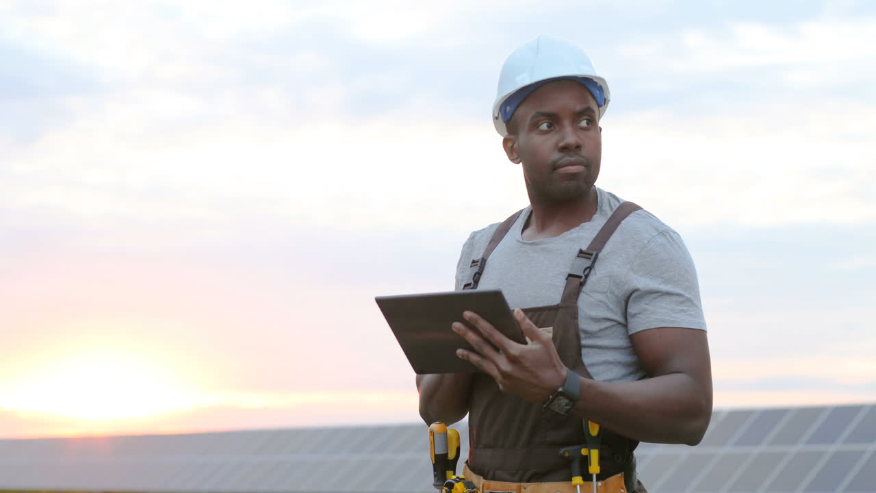 Young african american male engineer using a tablet on solar plantation